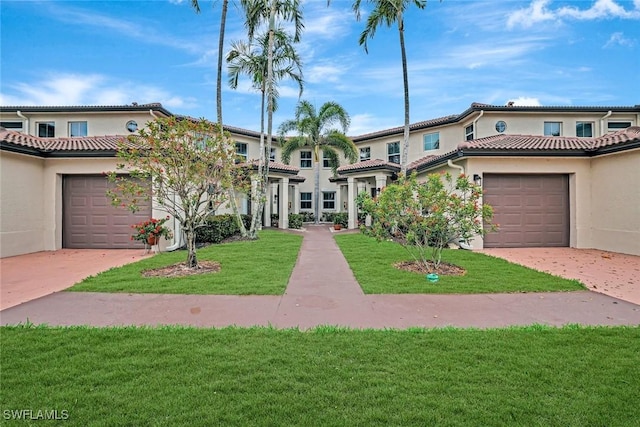 view of front of home with a garage, a tile roof, a front yard, and stucco siding