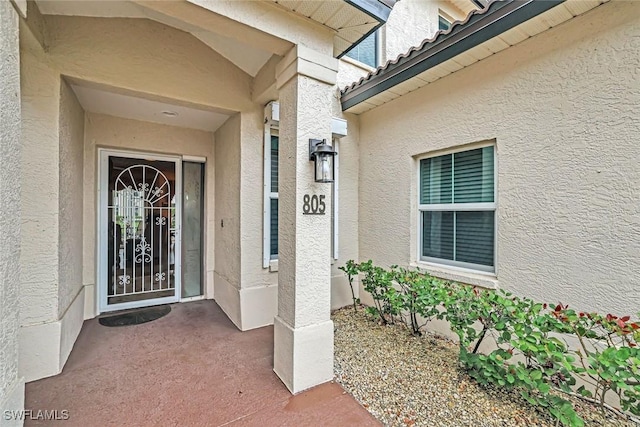 entrance to property with a tile roof and stucco siding