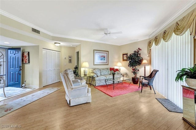 living area featuring ornamental molding, light wood-type flooring, a ceiling fan, and baseboards