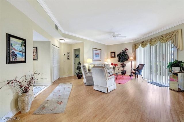 living room featuring baseboards, light wood-type flooring, visible vents, and crown molding