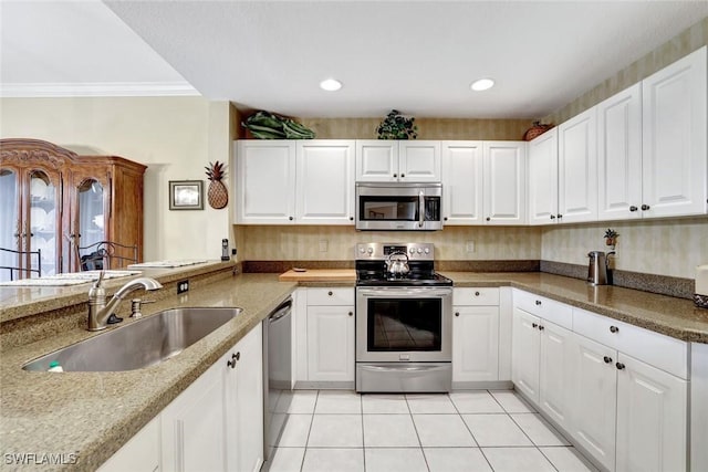 kitchen with light tile patterned floors, stainless steel appliances, a sink, and white cabinetry