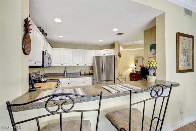 kitchen featuring a peninsula, visible vents, and appliances with stainless steel finishes