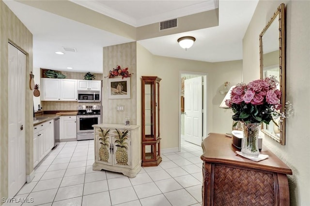 kitchen with light tile patterned floors, visible vents, appliances with stainless steel finishes, ornamental molding, and white cabinetry