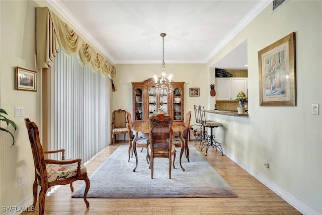 dining area with visible vents, baseboards, ornamental molding, light wood finished floors, and an inviting chandelier