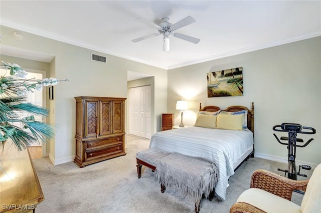 bedroom with light colored carpet, visible vents, baseboards, ornamental molding, and a closet