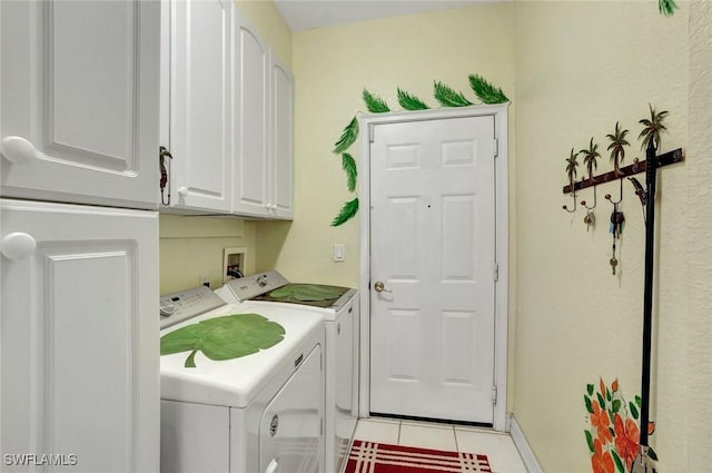 laundry area featuring light tile patterned floors, cabinet space, and washer and dryer