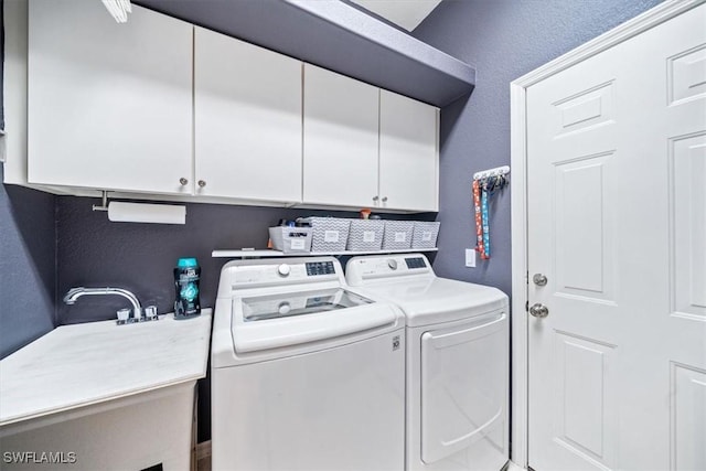 clothes washing area featuring a textured wall, independent washer and dryer, a sink, and cabinet space