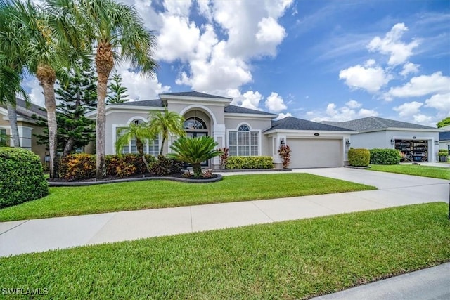 mediterranean / spanish-style home with a garage, a front yard, concrete driveway, and stucco siding