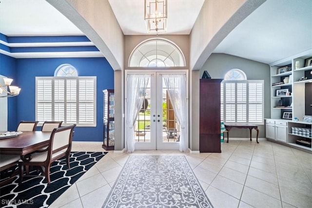 foyer entrance with light tile patterned floors, baseboards, arched walkways, an inviting chandelier, and french doors