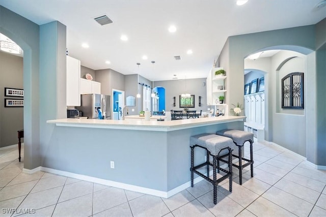 kitchen featuring light tile patterned floors, stainless steel fridge, a breakfast bar area, and light countertops