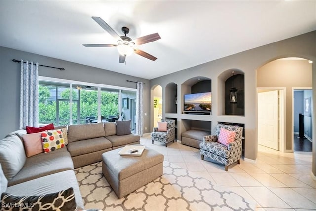 tiled living room with arched walkways, ceiling fan, and baseboards