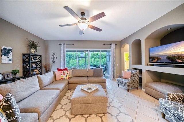 living room featuring light tile patterned floors, arched walkways, and a ceiling fan