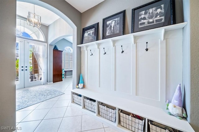 mudroom featuring tile patterned flooring, arched walkways, a notable chandelier, and french doors