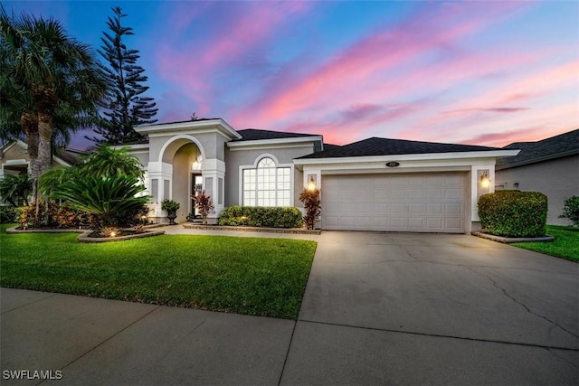 mediterranean / spanish home featuring a garage, concrete driveway, a front lawn, and stucco siding