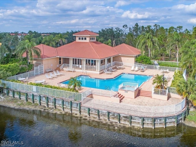 rear view of house with a patio, a fenced backyard, a tiled roof, a water view, and a community pool