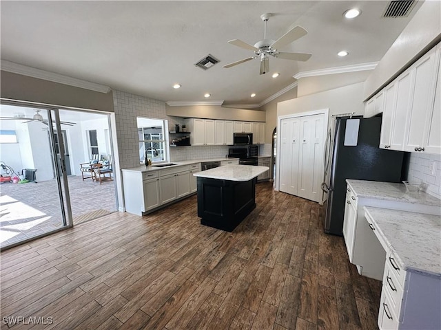 kitchen with dark wood-type flooring, visible vents, lofted ceiling, and a center island