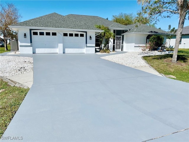 ranch-style home with stucco siding, an attached garage, concrete driveway, and a shingled roof