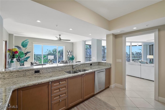 kitchen featuring dishwasher, light stone counters, a sink, and a wealth of natural light