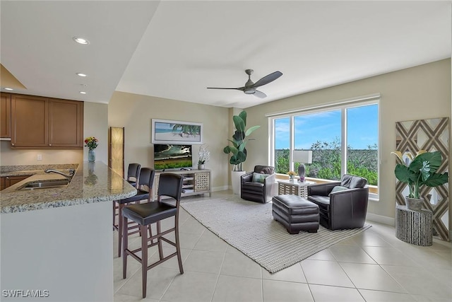 living area featuring light tile patterned floors, baseboards, a ceiling fan, and recessed lighting