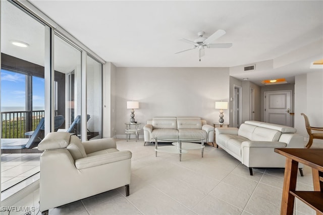 living area featuring expansive windows, light tile patterned flooring, visible vents, and a ceiling fan