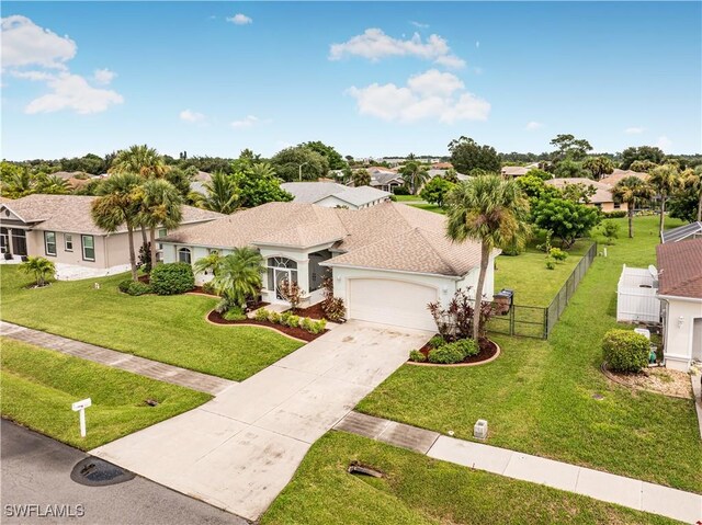 ranch-style home featuring concrete driveway, a residential view, an attached garage, fence, and a front yard