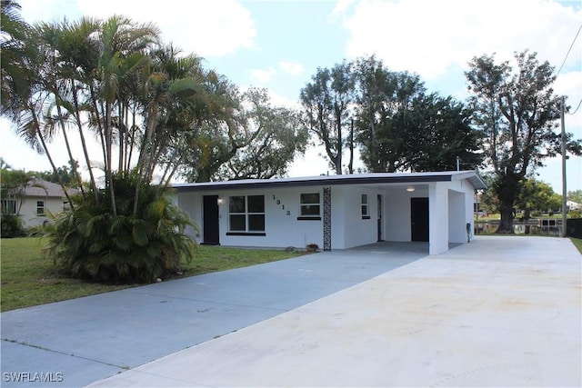 view of front of property featuring a front yard, concrete driveway, an attached carport, and stucco siding