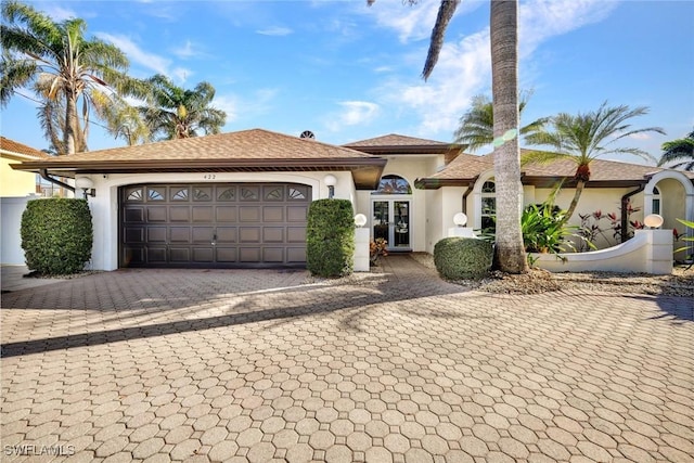 view of front of home featuring a garage, french doors, decorative driveway, and stucco siding