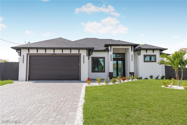 prairie-style house with a garage, fence, decorative driveway, and stucco siding