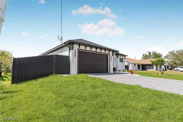 view of front of house featuring a garage, fence, decorative driveway, a front lawn, and stucco siding