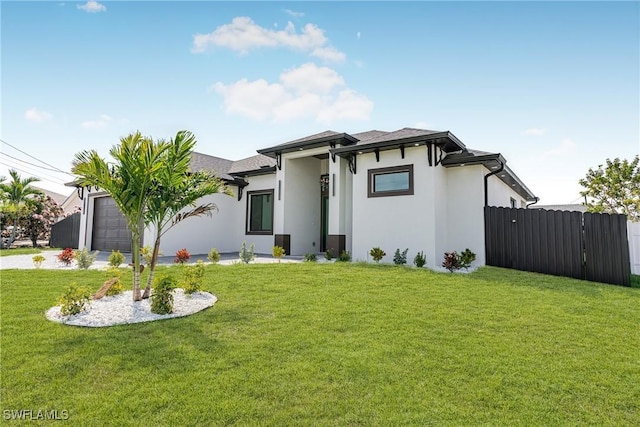 prairie-style home with a garage, driveway, fence, a front lawn, and stucco siding