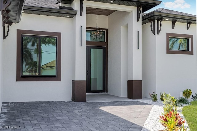 entrance to property featuring a shingled roof and stucco siding