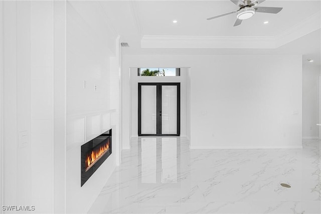 unfurnished living room featuring a warm lit fireplace, ornamental molding, a tray ceiling, and french doors