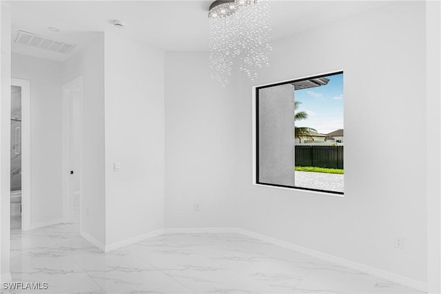 spare room featuring baseboards, marble finish floor, visible vents, and a notable chandelier