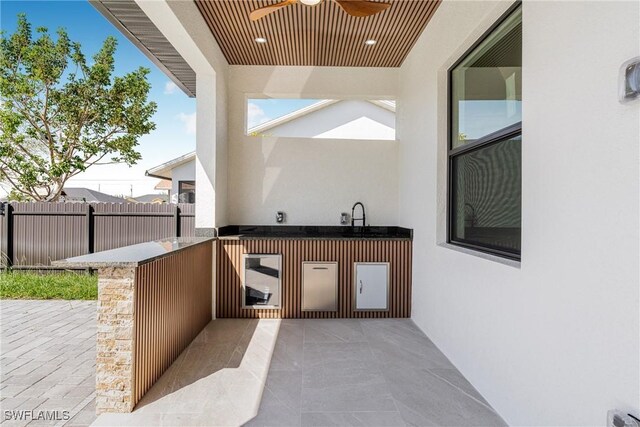 view of patio with fence, an outdoor kitchen, and ceiling fan