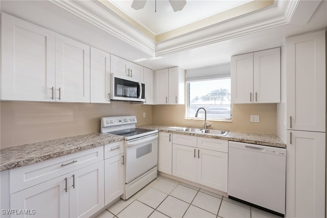 kitchen with white appliances, crown molding, a tray ceiling, and a sink