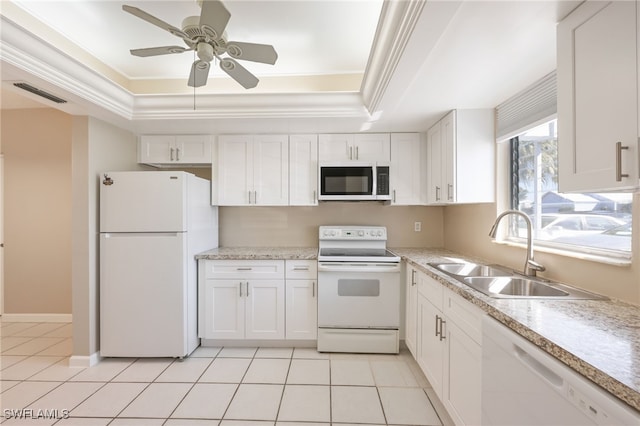 kitchen with white appliances, visible vents, a tray ceiling, crown molding, and a sink