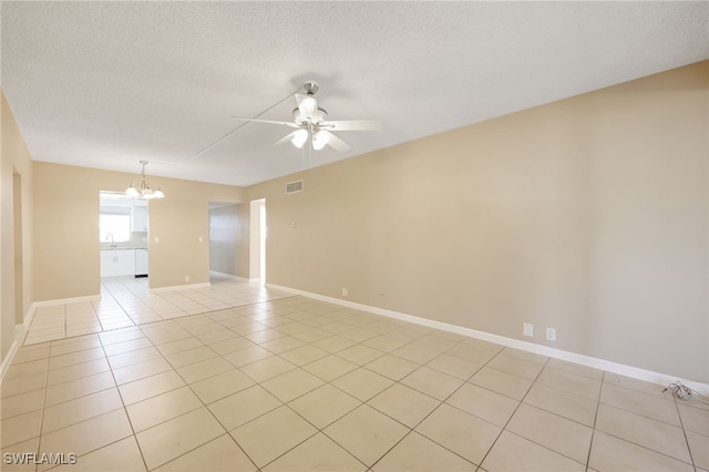 unfurnished room with light tile patterned flooring, a textured ceiling, baseboards, and ceiling fan with notable chandelier