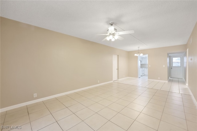 spare room featuring ceiling fan with notable chandelier, light tile patterned floors, a textured ceiling, and baseboards