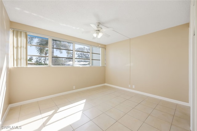 unfurnished room featuring a textured ceiling, baseboards, a ceiling fan, and light tile patterned flooring