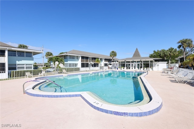 pool with a patio area and fence