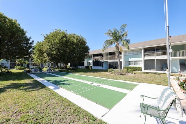 view of home's community with shuffleboard and a yard