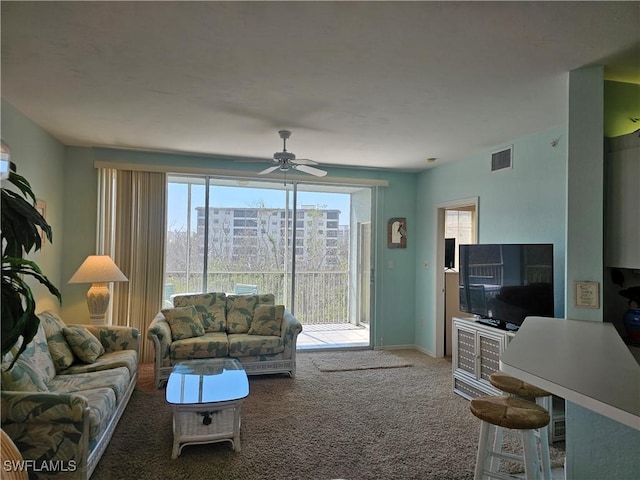 living area featuring carpet floors, visible vents, ceiling fan, and baseboards