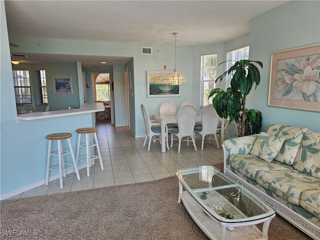 living room featuring carpet floors, plenty of natural light, visible vents, and tile patterned flooring