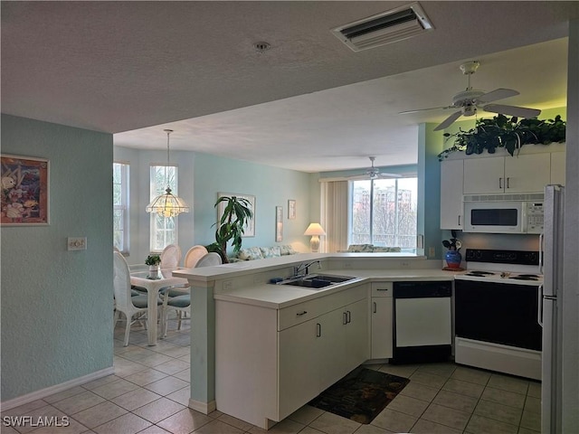 kitchen with a peninsula, white appliances, plenty of natural light, and visible vents