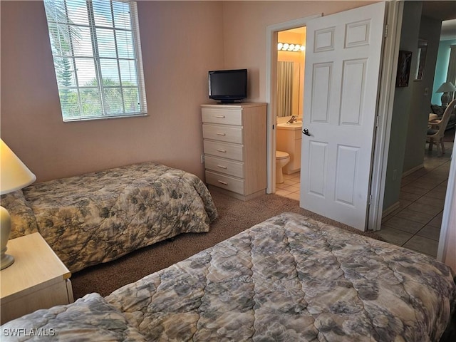 bedroom with carpet floors, connected bathroom, and tile patterned floors