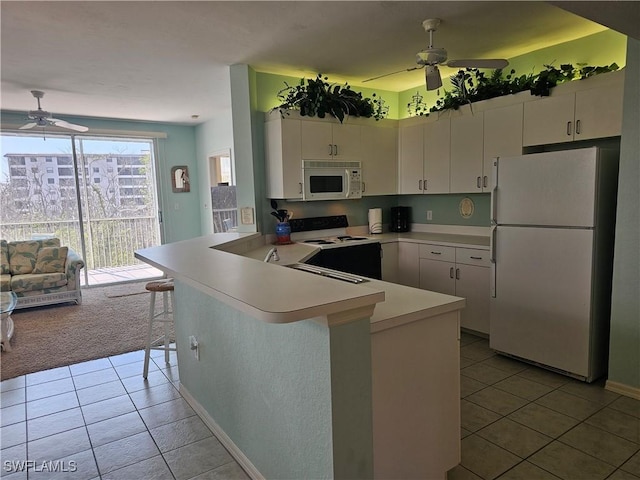 kitchen featuring a peninsula, white appliances, light countertops, and white cabinetry