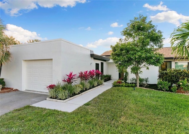 view of front of house with a garage, driveway, a front yard, and stucco siding