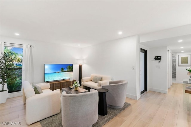 living area featuring recessed lighting, baseboards, and light wood finished floors