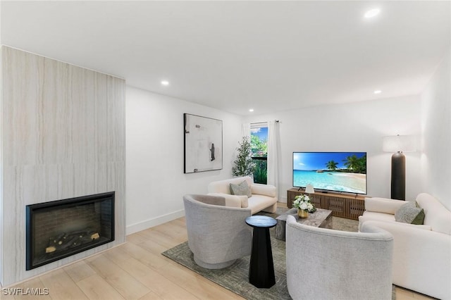 living area with recessed lighting, a fireplace, baseboards, and wood finished floors