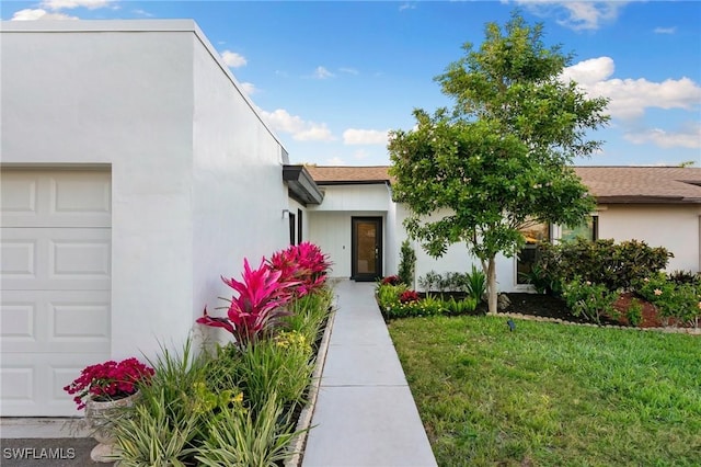 view of front of house featuring a garage, stucco siding, and a front yard